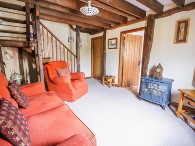 a living room with a couch and a wood stove at Beech Cottage in Llanidloes