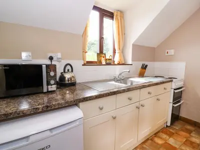 a kitchen with a sink and a microwave at Oak Cottage in Llanidloes