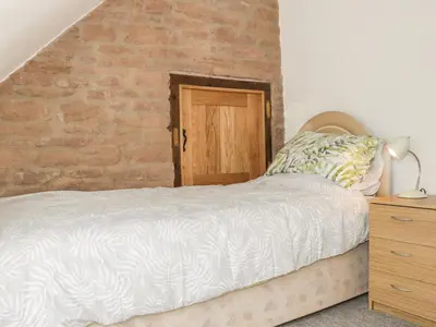 a bedroom with a bed and a brick wall at The Cow Byre, Heath Farm in Clee Saint Margaret