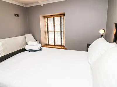 a bedroom with a large white bed and a window at Water Street in Aberaeron