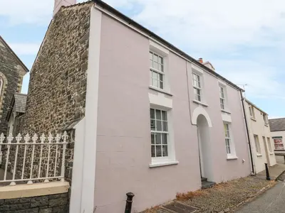 a pink house with a stone wall at Water Street in Aberaeron