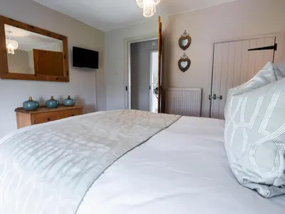 a bedroom with a white bed and a mirror at Cefn Uchaf Cottage in Llanbedr
