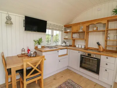 a kitchen with white cabinets and a wooden table at Hillside View in Saint Harmon