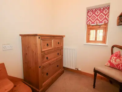 a bedroom with a wooden dresser and a window at Old Hall Barn 1 in Church Stretton