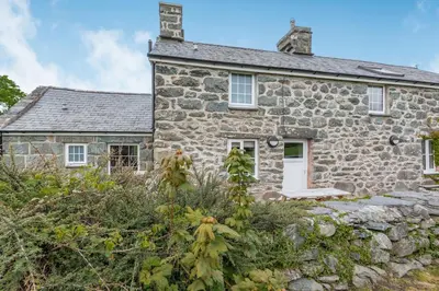 an old stone house with a stone wall at Gwrtheyrn in Dyffryn