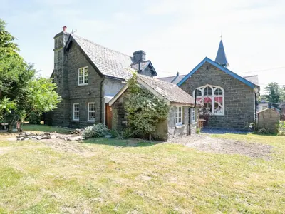 an old stone house with a large yard at School House in Builth Wells