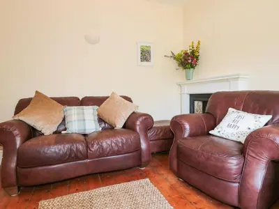 a living room with two brown leather couches and a fireplace at School House in Builth Wells
