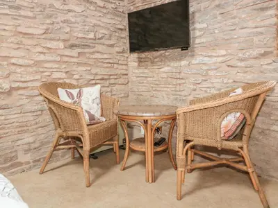 a table and two chairs and a tv on a wall at The Cow Cott in Peterchurch