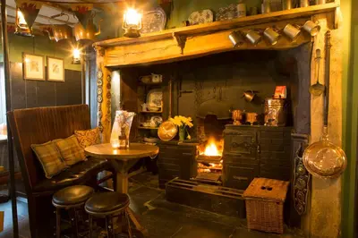 a room with a fireplace and a table and a chair at Victoria Inn in Llanbedr