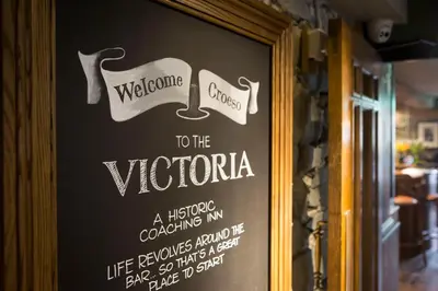 a sign on the door of a restaurant with a welcome sign at Victoria Inn in Llanbedr