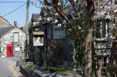 a building with a sign on it with a tree at Victoria Inn in Llanbedr