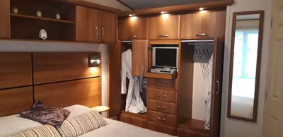 a bedroom with a bed and a tv and wooden cabinets at Dyfed 23 in Borth