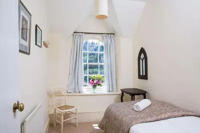 a bedroom with a bed and a window with a vase of flowers at The Old House, Llwyn Madoc in Llanwrtyd Wells
