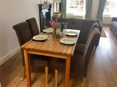 a dining room table with chairs and a wooden table with glasses at 2 Yr Hen Fanc in Aberaeron