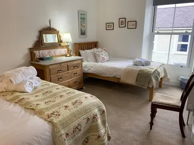 a bedroom with two beds and a dresser and a mirror at Awelfryn in New Quay