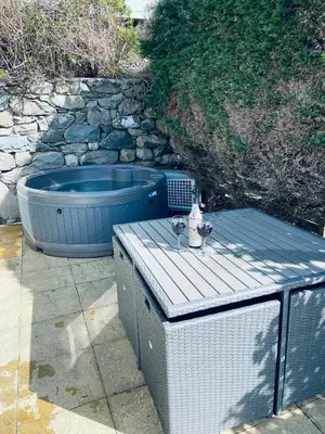 a patio with a hot tub and a table with wine glasses at Hendre Coed Isaf Caravan Park in Barmouth