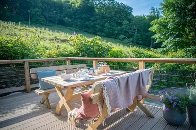 a wooden table and chairs on a wooden deck at Little Kestrel Cabin in Pennal