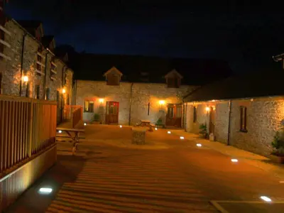 a courtyard at night with a bench and lights at The Carthouse in Aberystwyth