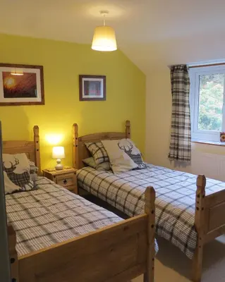 a bedroom with two beds and a window at Yr Hen Farcdy in Talsarnau