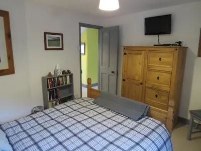 a bedroom with a bed and a dresser and a television at Yr Hen Farcdy in Talsarnau