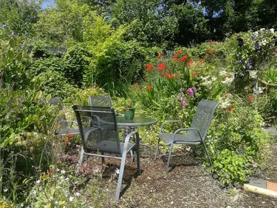 a table and chairs in a garden with flowers at Yr Hen Farcdy in Talsarnau