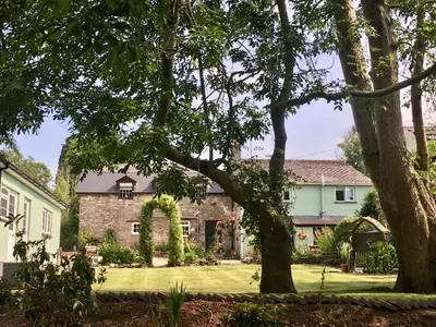 a house with a yard with trees in the foreground at Brecon Boutique Breaks River Run in Sennybridge