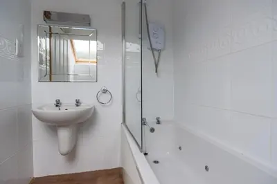 a white bathroom with a sink and a bath tub at The Workshop in Aberystwyth