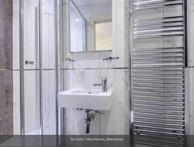 a white bathroom with a sink and a shower at Westhaven One in Aberdyfi