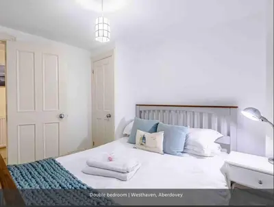 a bedroom with a bed with towels on it at Westhaven One in Aberdyfi