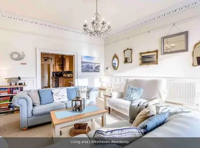 a living room with couches and a chandelier at Westhaven One in Aberdyfi
