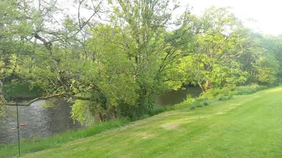 a river with trees and grass next to a field at 28 Riverside, Caer Beris Holiday Park in Builth Wells