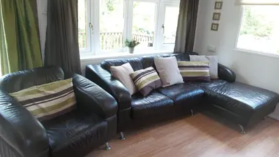 a leather couch in a living room with pillows on it at 28 Riverside, Caer Beris Holiday Park in Builth Wells
