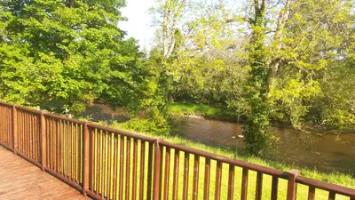 a view of a river from a wooden bridge at 28 Riverside, Caer Beris Holiday Park in Builth Wells