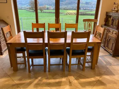 a wooden dining room table with chairs and a large window at Pentrego Isaf in Meifod
