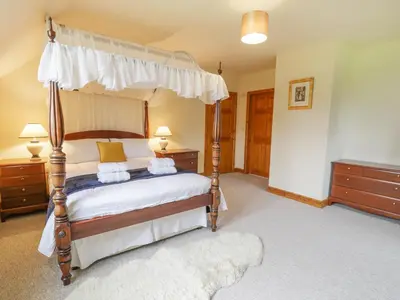 a bedroom with a canopy bed and two dressers at Pentrego Isaf in Meifod