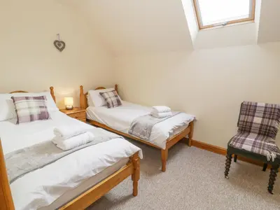 a small room with two beds and a chair at Pentrego Isaf in Meifod