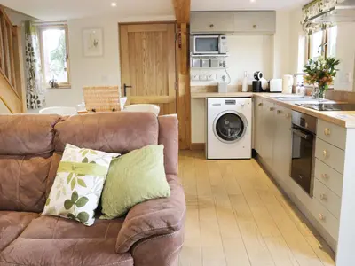 a living room with a couch and a kitchen at Acorn Cottage in Ludlow