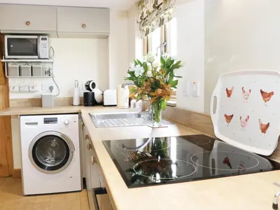 a kitchen with a washing machine and a vase of flowers at Acorn Cottage in Ludlow