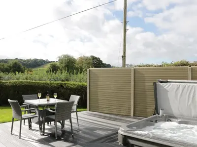 a patio with a table and chairs and a hot tub at Acorn Cottage in Ludlow