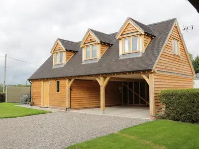 a large wooden house with a large garage at Acorn Cottage in Ludlow
