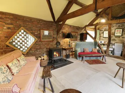 a living room with a brick wall and a fireplace at Dolgenau Hir - The Barn in Trefeglwys
