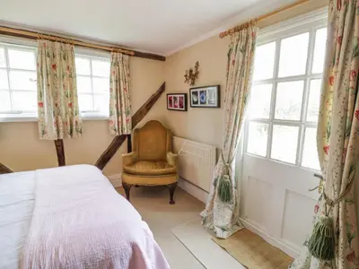 a bedroom with a bed and a chair and windows at Dolgenau Hir - The Barn in Trefeglwys