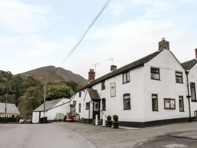a white house in a street with mountains in the background at The Hayloft in Shelve