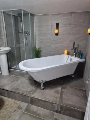 a white bath tub in a bathroom with a shower at Penbryn Holidays No 2 in Barmouth