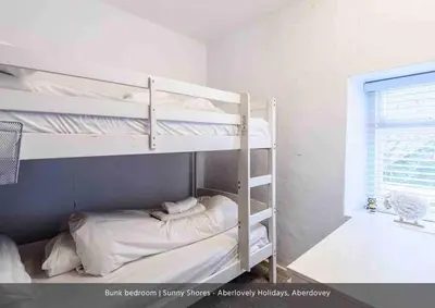 a bedroom with two bunk beds and a window at Sunny Shores in Aberdyfi