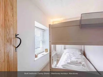 a bunk bed in a small room with a window at Sunny Shores in Aberdyfi