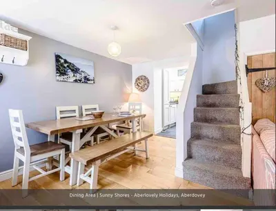 a dining room and kitchen with a table and a staircase at Sunny Shores in Aberdyfi