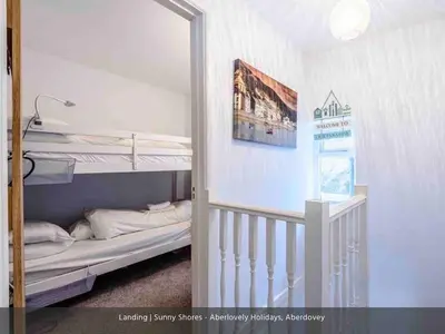 a room with two bunk beds and a staircase at Sunny Shores in Aberdyfi