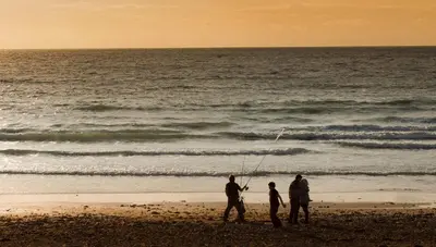 a group of people standing on a beach fishing at Enlli Fach cabin sleep's 2 adults and 2 children 2 dogs welcome not suitable for contract workers due to parking height restrictions in Borth