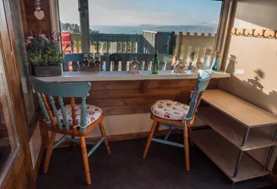 two chairs sitting next to a bar with a window at Enlli Fach cabin sleep's 2 adults and 2 children 2 dogs welcome not suitable for contract workers due to parking height restrictions in Borth